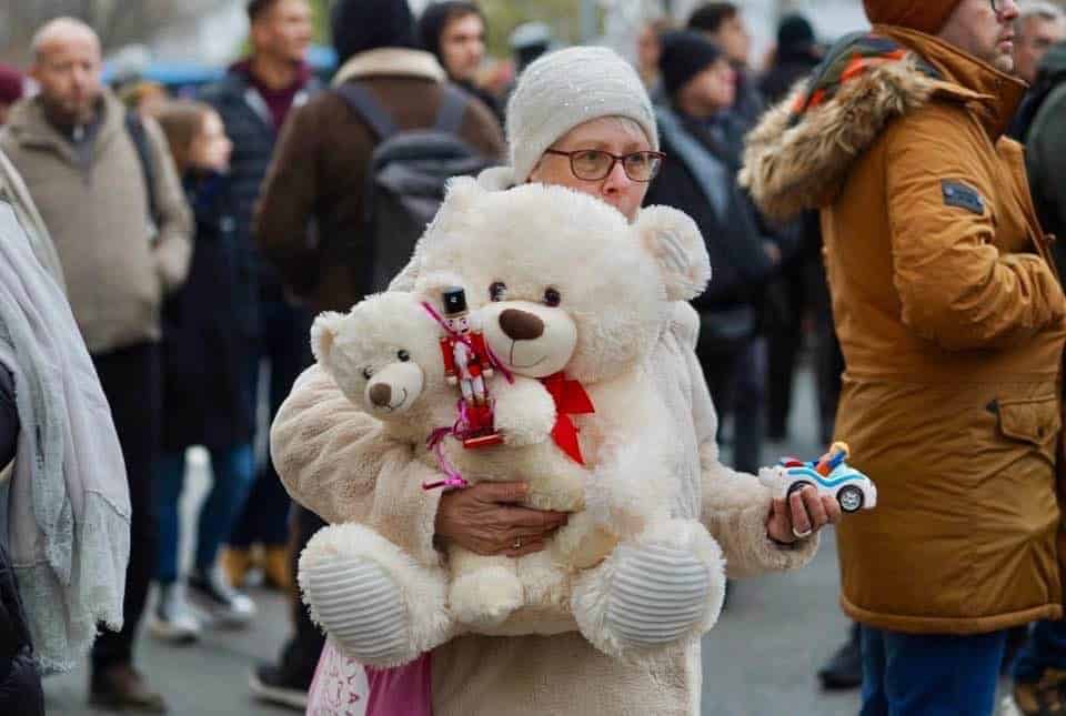 Baba nyuszi papucs, játék és plüssmackó, több száz ember a háttérben egy nyilvános eseményen.