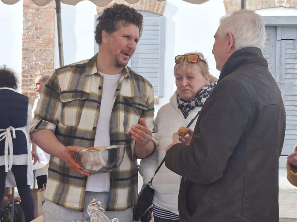 Fesztiválon részt vevő emberek kolbásztöltésről beszélgetnek.