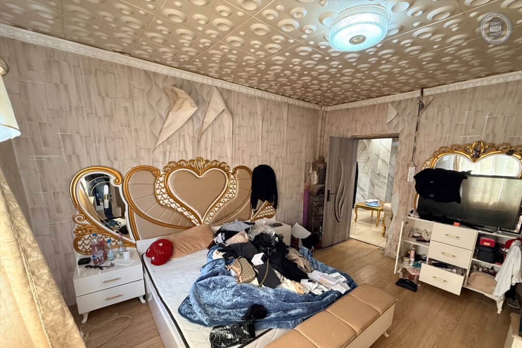 Az ágy mellett tükör és éjjeliszekrény, a szobában szekrény és televízió található.